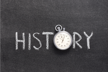 The word "History" written in chalk on a black board with a pocket watch as the "o"